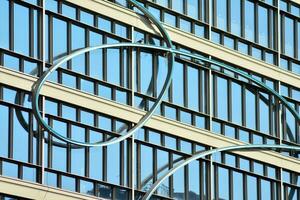 Structural glass wall reflecting blue sky. Abstract modern architecture fragment. photo