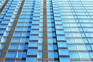 Structural glass wall reflecting blue sky. Abstract modern architecture fragment. photo