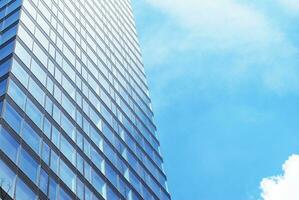 Structural glass wall reflecting blue sky. Abstract modern architecture fragment. photo