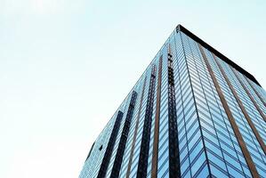 Structural glass wall reflecting blue sky. Abstract modern architecture fragment. photo