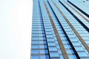 Structural glass wall reflecting blue sky. Abstract modern architecture fragment. photo