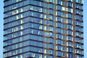 Structural glass wall reflecting blue sky. Abstract modern architecture fragment. photo