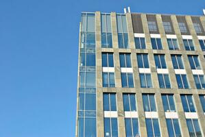 Structural glass wall reflecting blue sky. Abstract modern architecture fragment. photo