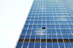 Structural glass wall reflecting blue sky. Abstract modern architecture fragment. photo