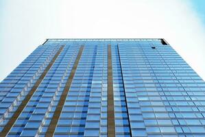 Structural glass wall reflecting blue sky. Abstract modern architecture fragment. photo