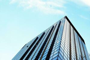 Structural glass wall reflecting blue sky. Abstract modern architecture fragment. photo