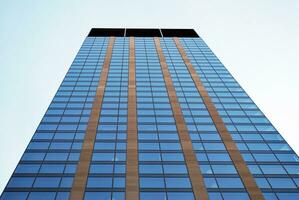 Structural glass wall reflecting blue sky. Abstract modern architecture fragment. photo