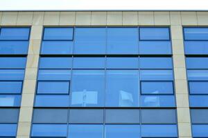 Structural glass wall reflecting blue sky. Abstract modern architecture fragment. photo