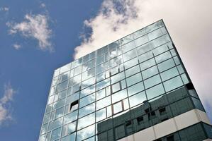 Structural glass wall reflecting blue sky. Abstract modern architecture fragment. photo