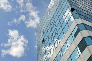 Structural glass wall reflecting blue sky. Abstract modern architecture fragment. photo