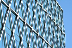 Structural glass wall reflecting blue sky. Abstract modern architecture fragment. photo