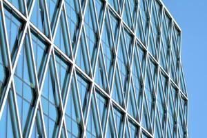 Structural glass wall reflecting blue sky. Abstract modern architecture fragment. photo