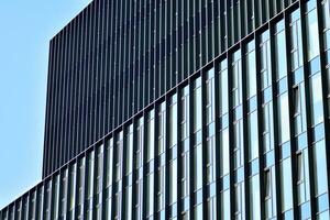 Structural glass wall reflecting blue sky. Abstract modern architecture fragment. photo