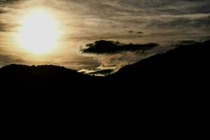 the sun is setting over a mountain range photo