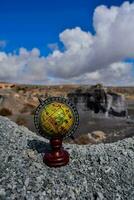 a globe on a rocky cliff photo