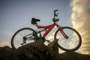 a red bike is sitting on top of a rock photo