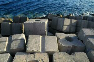 concrete blocks are stacked on the shore near the ocean photo
