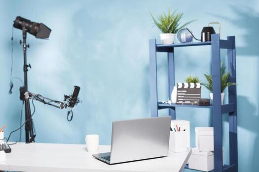 Blogger empty workplace with professional equipment and laptop on table ready for live streaming. Portable computer on desk and microphone in vlogger modern home studio with no people photo