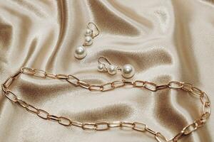 Women's jewelry, gold chain, trendy jewelry on a silk background. photo