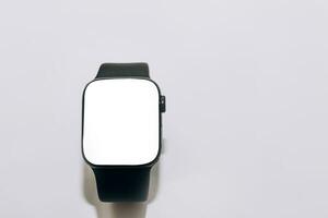 A black technological smart watch lies on a wooden background with a white screen for text space photo