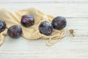 Reusable eco shopping bags with plums, replacing plastic bags photo