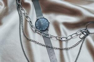 Stylish silver chain decorations for the neck and watch on a silk shiny background. photo