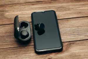 Wireless headphones in a black box on the table next to the phone. photo
