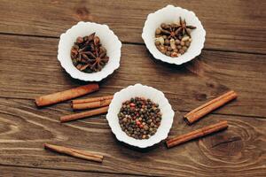 Spices anise, pepper, cumin, cumin, ginger in bowls on a wooden table photo