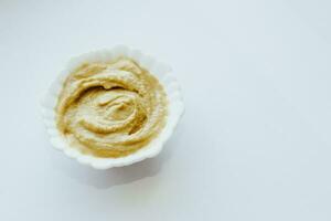 Mustard sauce in a white bowl on a white table. photo