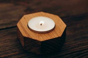 Wax and aromatic candle in a wooden candlestick stands on a wooden table. photo