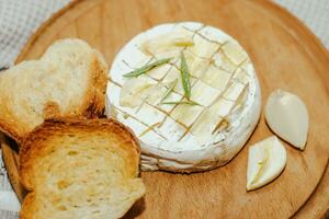 White baguette cut into pieces with olive oil and Camembert cheese on the table photo