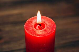 rojo iluminado aroma vela en de madera tableros antecedentes. foto
