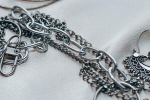 elegante plata cadena joyería en el cuello en un seda brillante antecedentes. foto