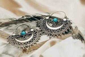 Ethnic stylish jewelry earrings on a silk golden background. photo