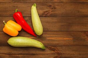 Red pepper Kapi with yellow sweet pepper and zucchini on a wooden background, space for text. photo