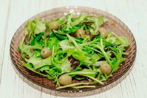 ensalada hojas con Rúcula y verde aceitunas en un lámina, sano dieta ensalada. foto