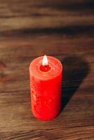 Red lit aroma candle on wooden boards background. photo