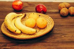 A wicker bowl with fruit stands on a wooden brown table. photo