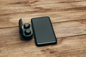 Wireless headphones in a black box on the table next to the phone. photo