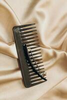 Elegant black hair clip and comb on a silk golden background. photo