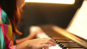 närbild av en liten studentens hand spelar de piano. Lycklig ung asiatisk flicka inlärning och praktiserande de piano. selektiv fokus. video