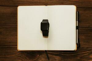 Open notebook diary with clock with black dial, time management concept. photo