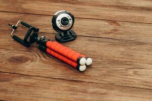 The phone stands on a manual monopod tripod for the camera on a wooden table.. photo