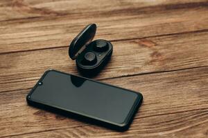 Wireless headphones in a black box on the table next to the phone photo
