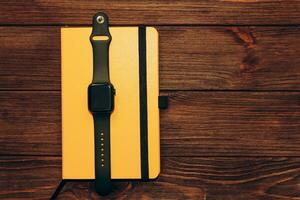 A black technological smart watch lies on a notepad for time management. photo