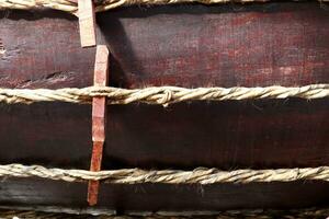 Old traditional style rope made from skin of cow on dark brown painted wood. photo