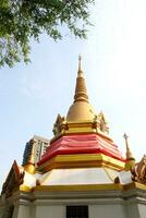 Golden color pagoda covered red cloth with white base and bright sky background. photo