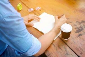 un hombre es escritura en un cuaderno con un taza de café foto