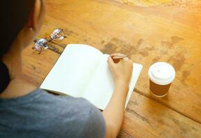 a woman writing in a notebook with a coffee cup photo