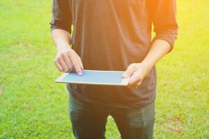 un hombre participación un tableta computadora en el césped foto